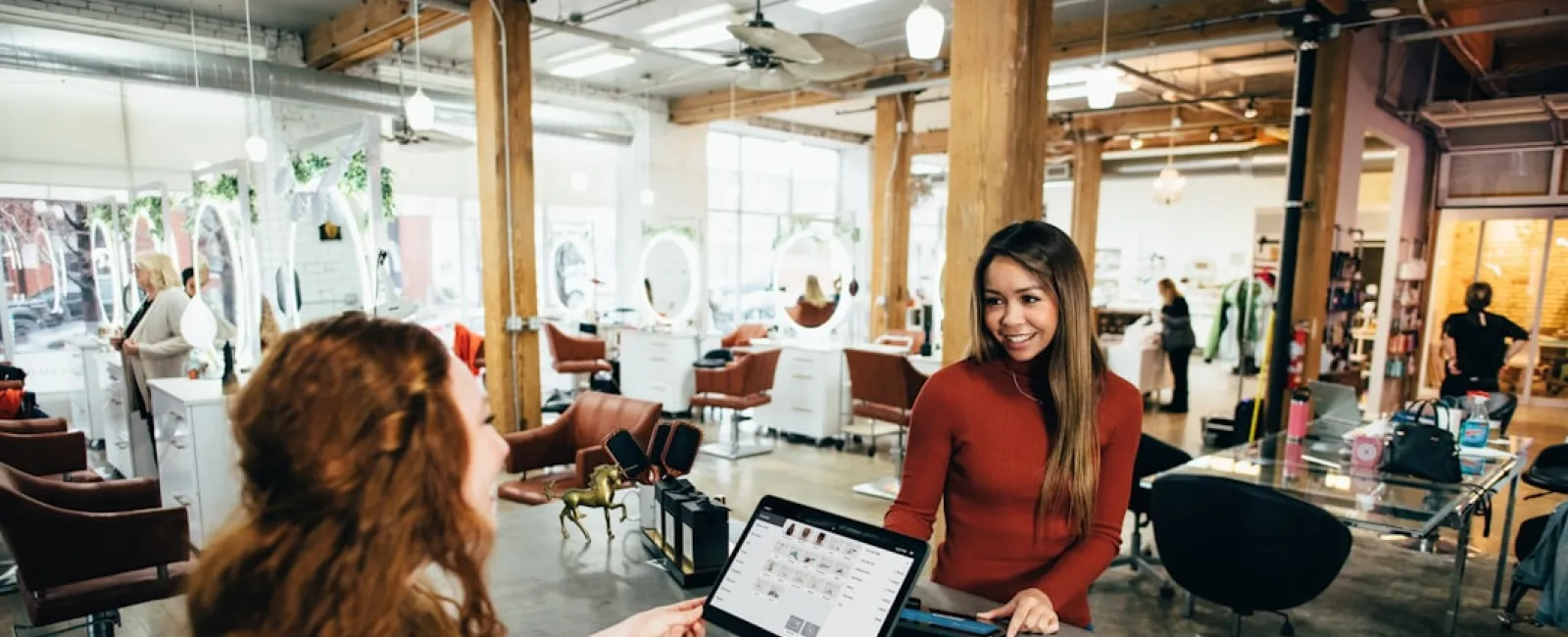 Customer checking out at a modern hair salon with wooden beams, bright lighting, and stylish chairs.